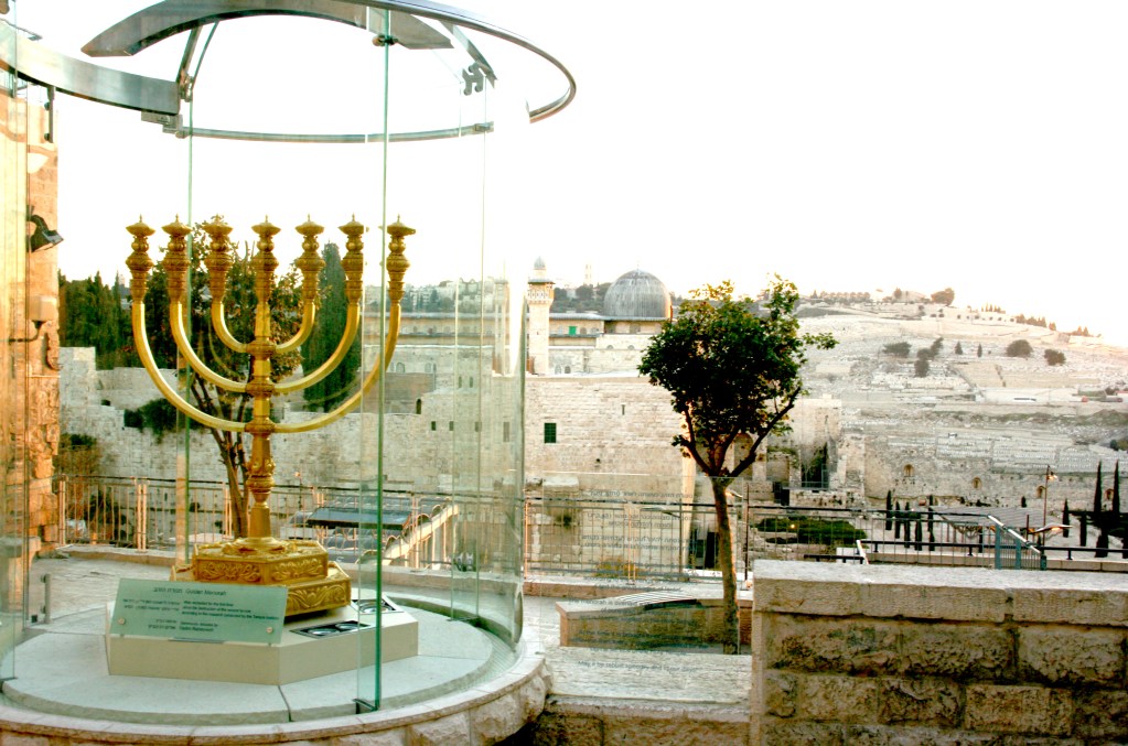 上图：从耶路撒冷圣殿研究所（The Temple Institute）门口的金灯台（Golden Menorah）俯瞰圣殿山的阿克萨清真寺（Al-Aqsa Mosque）。这个金灯台是圣殿研究所制造的，重500公斤，用了45公斤24K黄金，准备放到将来重建的第三圣殿里。目前，圣殿研究所已经完成了重建圣殿的大部分准备工作，剩下的最大难题就是殿址。因为第二圣殿的原址上建有伊斯兰教圣地岩石圆顶殿（Dome of the Rock），若要强行拆毁，后果不堪设想。圣殿研究所希望将岩石圆顶迁至另一个地点，而有些正统犹太人则认为第三圣殿只能在弥赛亚时代重建。目前，穆斯林拒绝承认岩石圆顶是第二圣殿的原址，并且不允许进行考古挖掘；而不少犹太人和考古学家则认为，第二圣殿的确切地址可能在岩石圆顶以北或以南一百米左右。还有犹太人认为，未来的先知可以指定在摩利亚山的任何地点重建圣殿。因此，殿址问题并非无解，在历史上，岩石圆顶曾于1015年地震中倒塌。将来若有新的考古发现、地震或形势的变化，两殿共存也并非没有可能。重建圣殿是末日大灾难和基督再来的前兆，「一七之内，他必与许多人坚定盟约」（但九27），很可能是预言在敌基督的安排之下，以色列与伊斯兰世界达成了和平协议，圣殿得以重建。